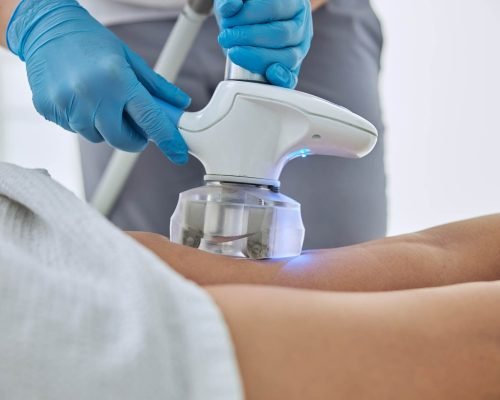 Cropped head portrait of beautician doing ultrasound cavitation body contouring treatment in wellness spa center